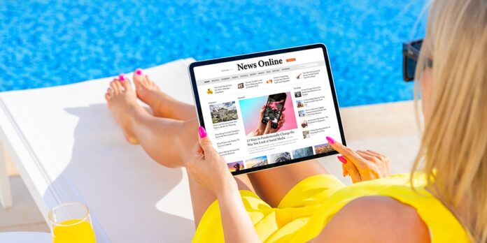 Woman relaxing on sunbed by the pool and reading news on tablet